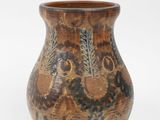 un vase brun orné d'un motif sur une surface blanche