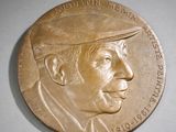une médaille de bronze représentant un homme coiffé d'un chapeau