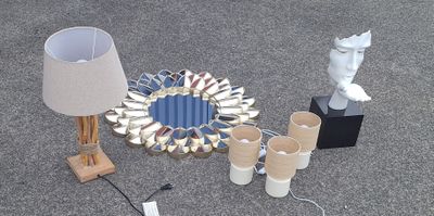 une table sur laquelle se trouvent une lampe, des vases, un miroir et d'autres objets