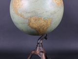 une image représentant un petit globe terrestre posé sur un socle, tenu par un homme