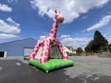 une grande girafe gonflable qui se trouve au milieu d'un parking