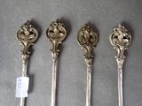 four spoons with ornate designs are lined up on a table