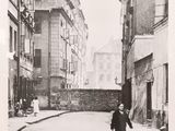 black and white photograph of a woman walking down a narrow street