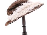 un chapeau marron orné de plumes blanches, posé sur un support noir