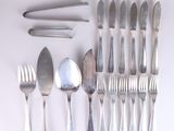 many forks and spoons laid out on a white surface