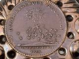 a bronze object with a coin on it on a white surface