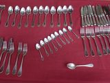 un grand nombre de cuillères et de fourchettes disposées sur une table
