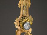 a gold clock on a marble table with a black background