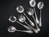 six silver spoons are arranged in a row on a black surface