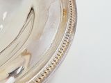 a silver plate with a silver handle on a white table