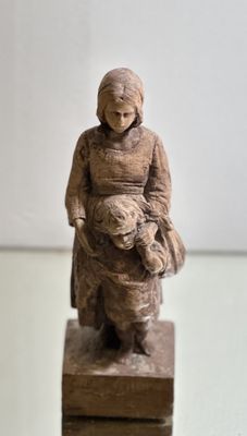 a statue of a woman holding a baby on a wooden block