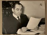 photographie en noir et blanc d'un homme en costume en train de lire un bout de papier