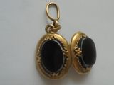 deux boucles dorées ornées de pierres noires, sur un fond blanc