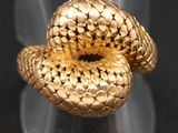un gros plan d'une bague en forme de serpent en or posée sur une surface noire
