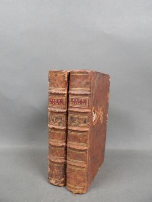 two old books are stacked on top of each other on a gray surface