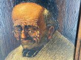 painting of an old man reading a book in a wooden frame