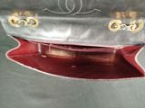 a silver purse with a red handle on a table