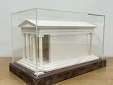 a small white model of a building in a glass case