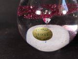 a glass vase filled with a pink liquid and a gold label