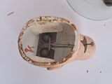 an old toilet with a broken lid and a broken toilet brush