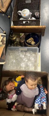 un petit enfant assis dans une boîte dans laquelle se trouve une poupée