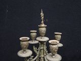 an antique bronze candelabra with five candles and a vase on a stand