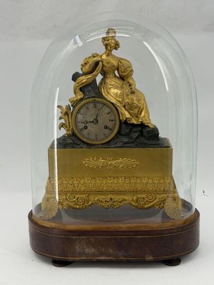 a gold clock under a glass dome on a table