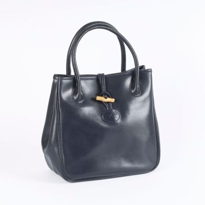 a black leather handbag with a wooden handle on a white background