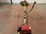 a small red and black lawn mower sitting on the floor