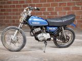a blue and black motorcycle parked in front of a brick wall