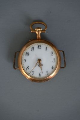 un gros plan d'une montre de poche en or posée sur une surface grise