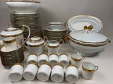 a lot of white and gold dishes and cups on the table