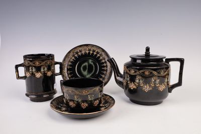 three pieces of black and gold decorated tea set on a white surface