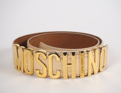 un gros plan sur une ceinture dorée portant l'inscription « Moschino »