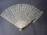 a close up of a white lace fan on a table