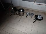 des casseroles et des poêles par terre dans une cuisine