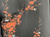 an image of a woman wearing a black jacket with orange and white flowers on it