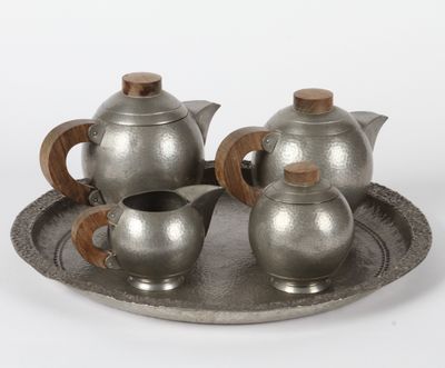 trois théières en argent posées sur un plateau en argent, sur fond blanc