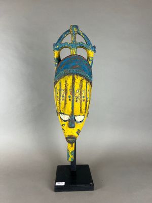 un masque jaune et bleu posé sur un socle noir