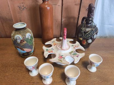 de nombreuses tasses et soucoupes posées sur une table, à côté d'une bouteille