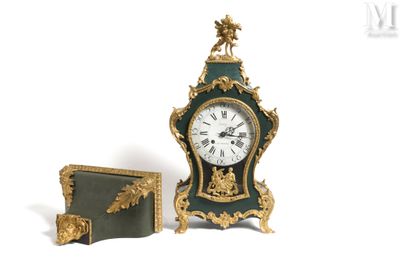 une horloge verte et dorée posée à côté d'un livre