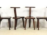 three wooden chairs sitting side by side against a white wall