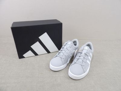 the adidas sneakers are on the floor next to a box