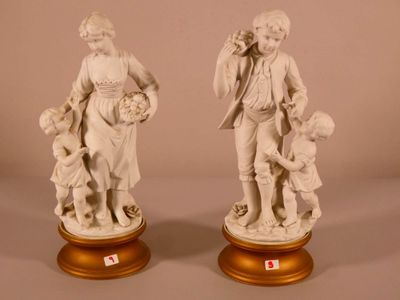 pair of white statues of a man and a woman with a child