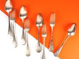 five silver spoons and two silver spoons on an orange and white background