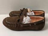 une paire de mocassins en daim marron posés sur une surface blanche