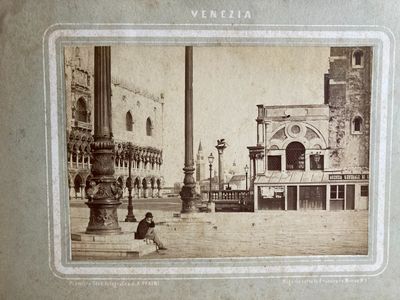 an old photo of a man sitting on a bench in front of a building
