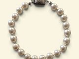 a close up of a white pearl bracelet with a silver clasp