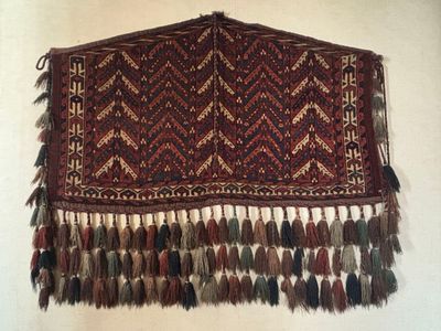 un grand tapis rouge et marron orné de pompons, accroché au mur