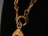 a gold necklace with a glass pendant on a black mannequin